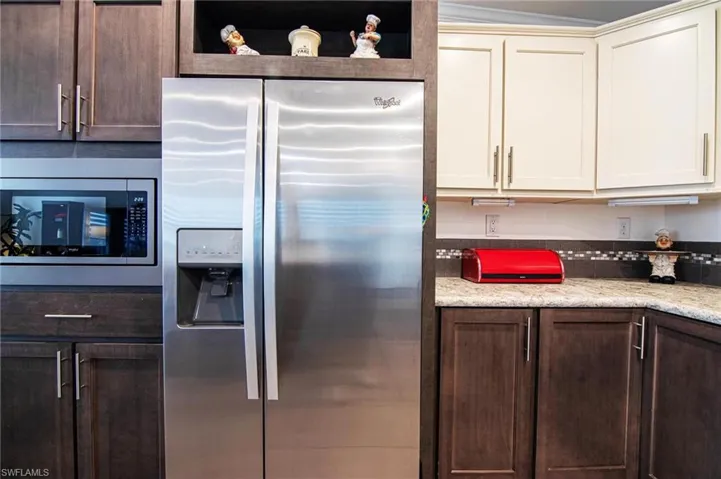 Kitchen featuring stainless steel fridge, dark brown cabinets, and open shelves