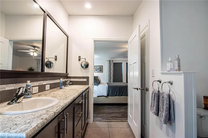 Bathroom with double vanity, dark tile patterned flooring, connected bathroom, and ceiling fan