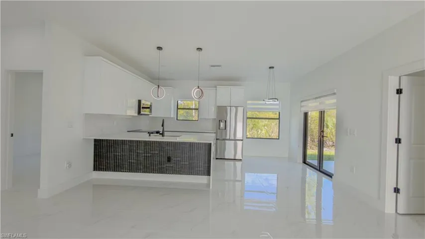 Kitchen featuring white cabinets, appliances with stainless steel finishes, a peninsula, decorative light fixtures, and modern cabinets