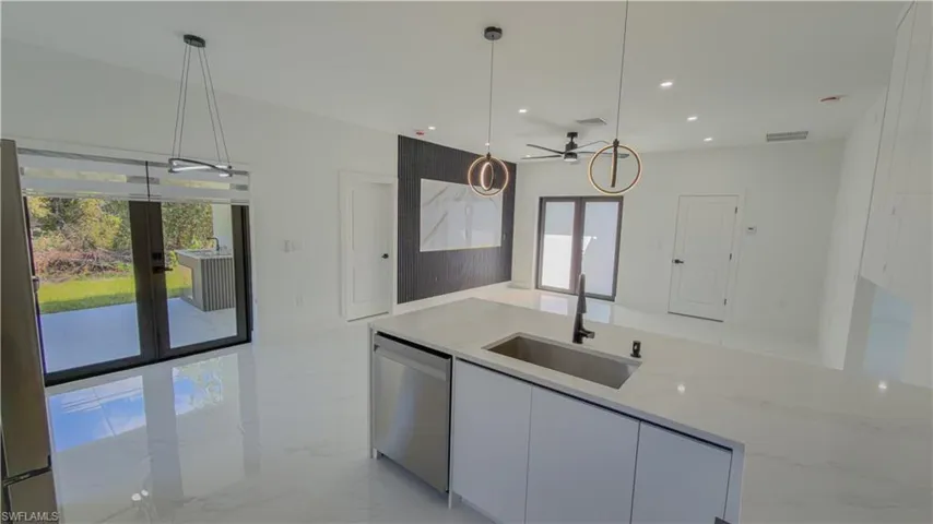 Kitchen with plenty of natural light, light stone countertops, light marble finish floors, decorative light fixtures, and recessed lighting
