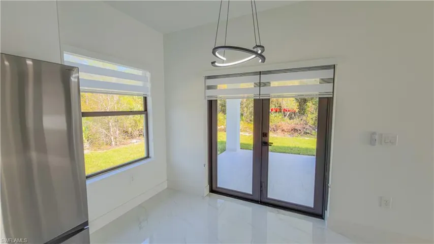 Unfurnished dining area featuring light marble finish flooring and french doors