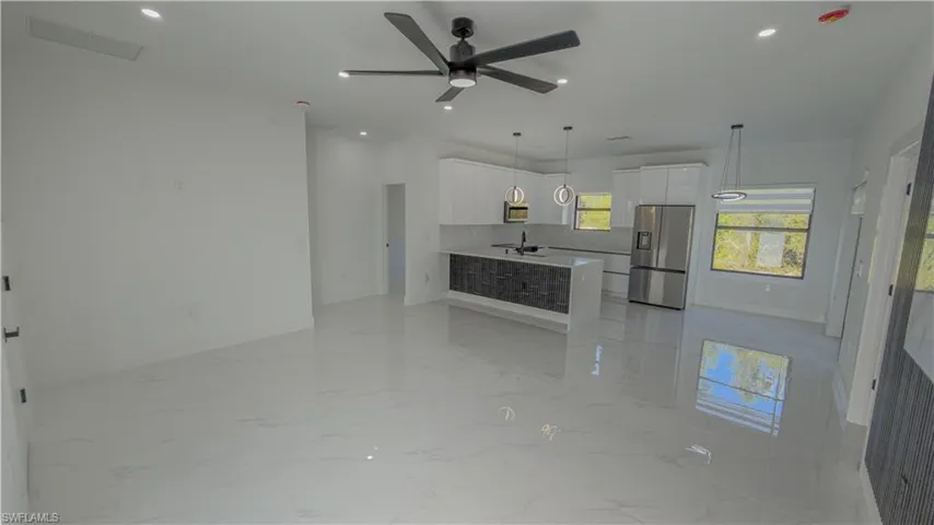Unfurnished living room with light marble finish floors, ceiling fan, and recessed lighting