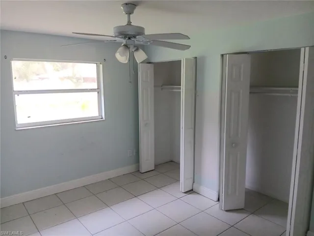 Unfurnished bedroom featuring two closets, light tile patterned flooring, and ceiling fan