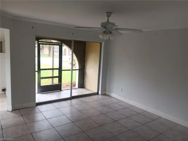 Empty room featuring ornamental molding, tile patterned floors, and ceiling fan