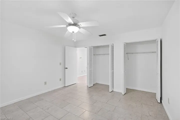 Unfurnished bedroom featuring two closets and ceiling fan
