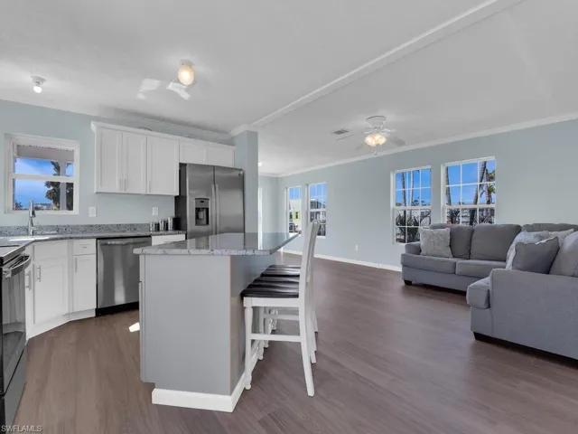 Kitchen with a kitchen island, sink, white cabinets, a kitchen bar, and stainless steel appliances
