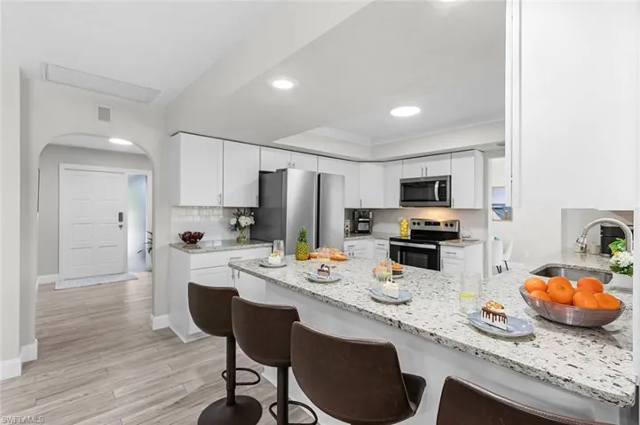 Kitchen featuring white cabinetry, light-toned countertops, a stainless steel refrigerator, and recessed lighting