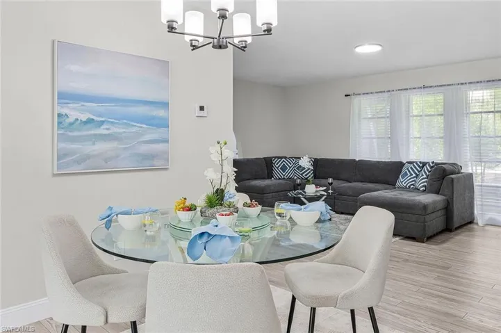 Open-concept living space featuring wood-finish flooring, a modern chandelier, and large windows
