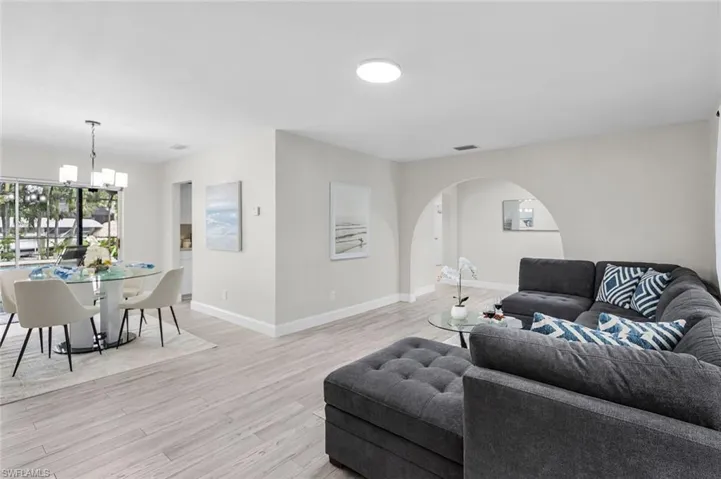 Wood-finish flooring throughout, arched entryway, recessed ceiling lighting, and a chandelier in the dining area