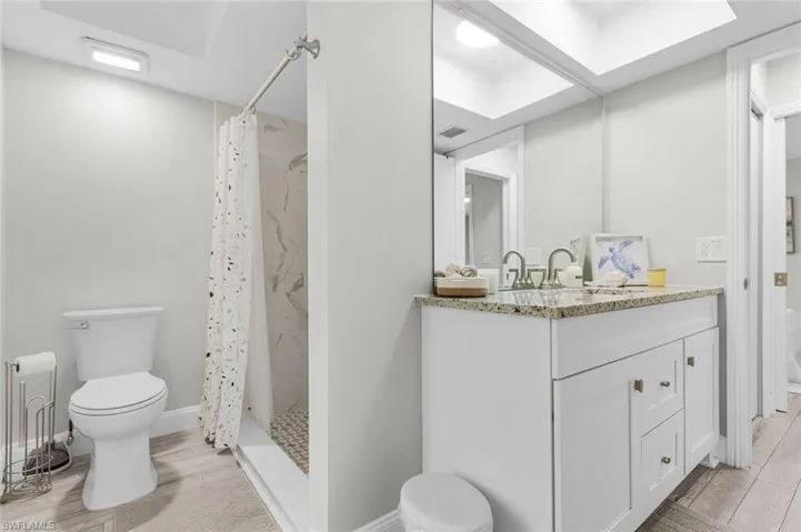 White vanity with granite countertop, dual basin sink, and chrome fixtures