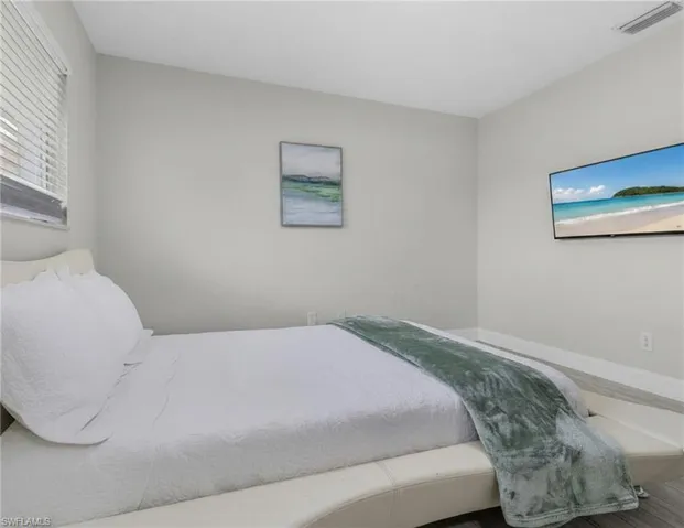 Window blinds, wall-mounted television, wood-finish flooring, light-toned walls