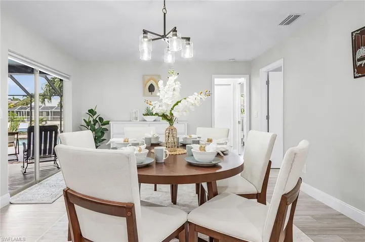 Recessed lighting, contemporary chandelier, sliding glass doors, light wood-finish flooring, and white baseboards