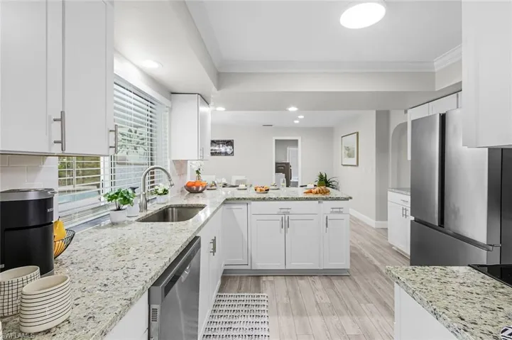Kitchen featuring white cabinetry, light-colored countertops, stainless steel appliances, and wood-finish flooring