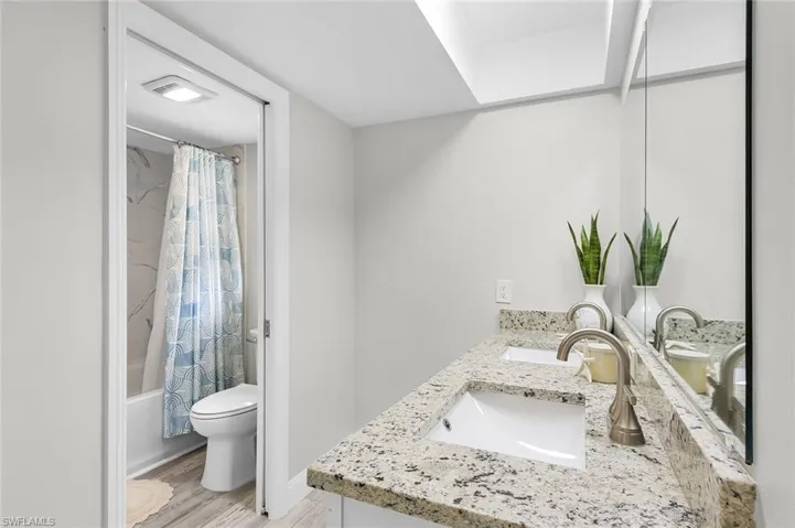 Dual vanity with undermount sinks, stone countertop, brushed nickel fixtures, and a large wall-mounted mirror