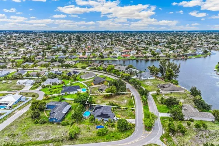 Cleared land parcel bordered by a paved road, surrounded by established residential properties