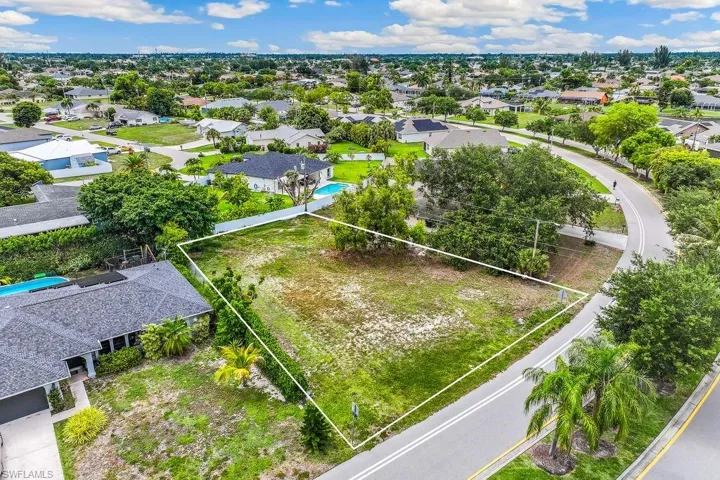 Cleared land parcel, bordered by paved roadways and established residences