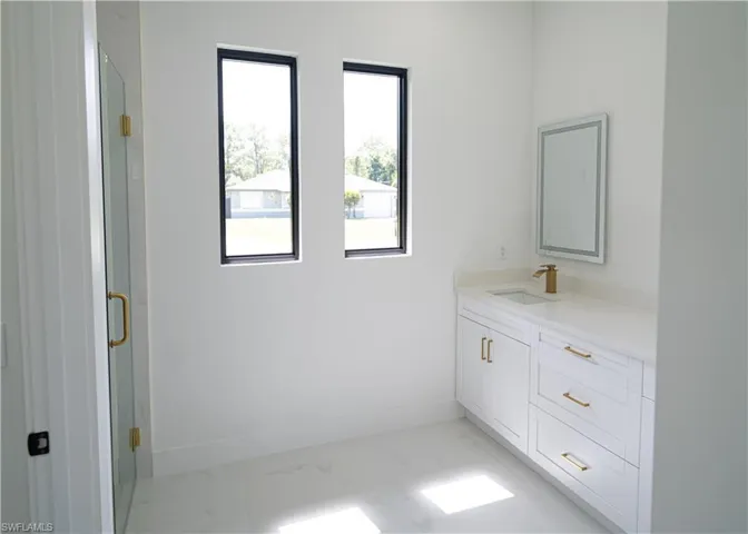 Bathroom with vanity, a marble finish shower, and light marble finish floors