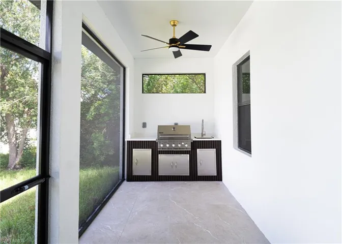 Unfurnished sunroom with exterior kitchen and a ceiling fan