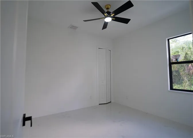Empty room featuring light marble finish floors and a ceiling fan