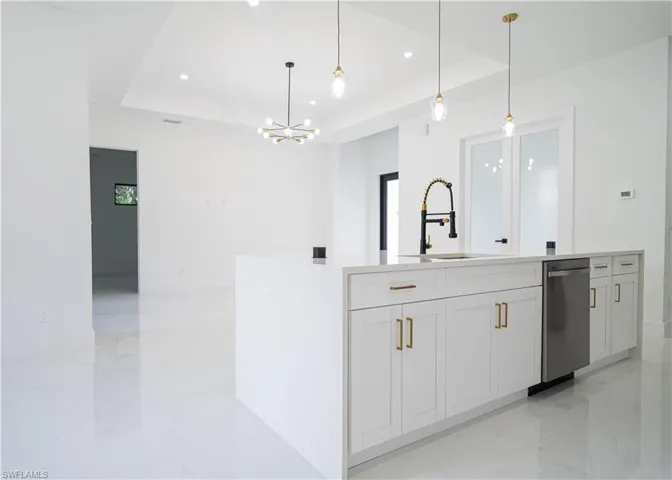 Kitchen with a raised ceiling, light marble finish floors, light stone countertops, decorative light fixtures, and recessed lighting