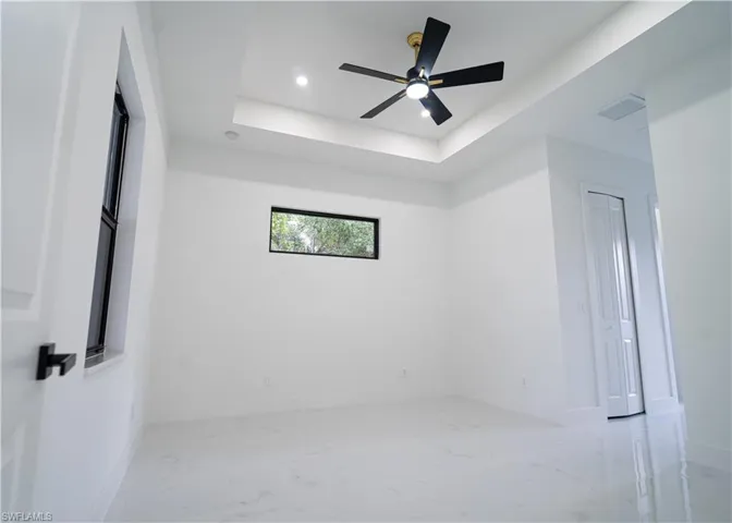 Empty room with light marble finish flooring, ceiling fan, a tray ceiling, and recessed lighting