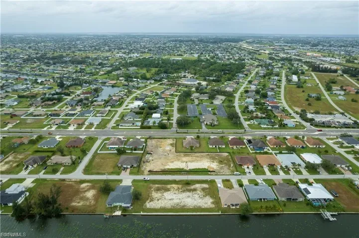 Aerial view of property and surrounding area featuring nearby suburban area and a large body of water