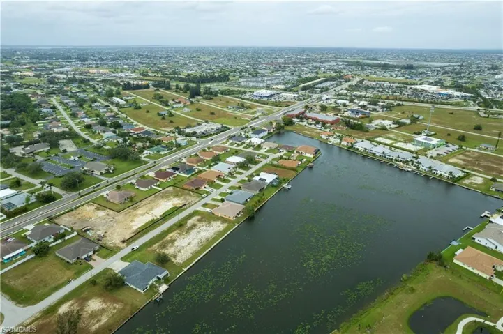 Aerial view of property and surrounding area featuring a nearby body of water and nearby suburban area