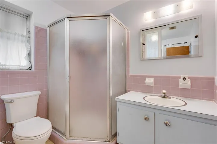 Full bath featuring vanity, a shower stall, and tile walls