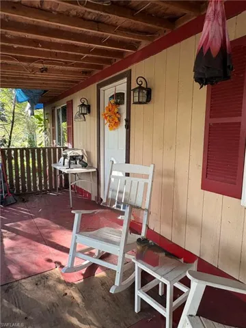 Covered porch featuring vertical board-and-batten siding, shutter-framed windows, and decorative wall-mounted exterior lighting