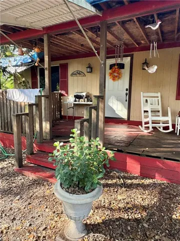 Covered front porch featuring a wood-deck floor, painted railing, and exterior wall-mounted lanterns