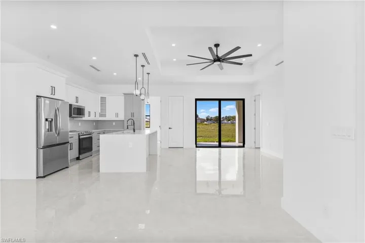 Kitchen with glass insert cabinets, white cabinets, appliances with stainless steel finishes, decorative light fixtures, and a raised ceiling