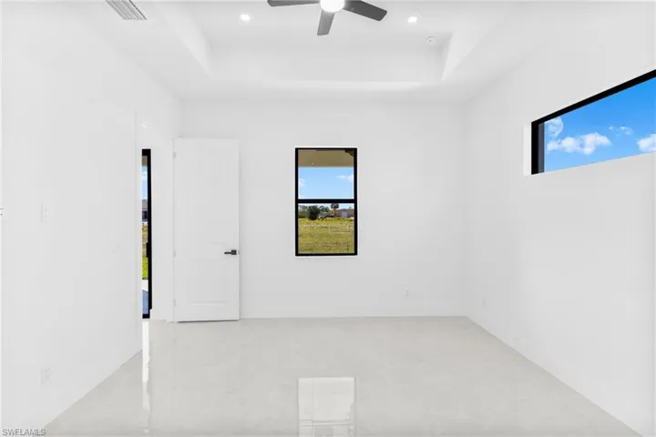 Unfurnished room featuring a tray ceiling, healthy amount of natural light, ceiling fan, and recessed lighting
