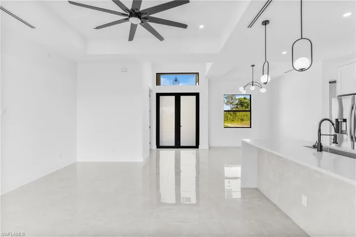 Entrance foyer with a tray ceiling, recessed lighting, a ceiling fan, light tile patterned floors, and a chandelier