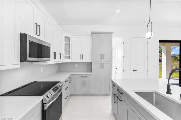Kitchen featuring appliances with stainless steel finishes, hanging light fixtures, decorative backsplash, recessed lighting, and glass insert cabinets