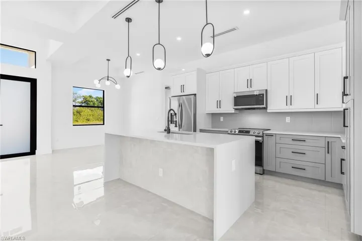Kitchen with decorative backsplash, appliances with stainless steel finishes, an island with sink, light stone counters, and recessed lighting