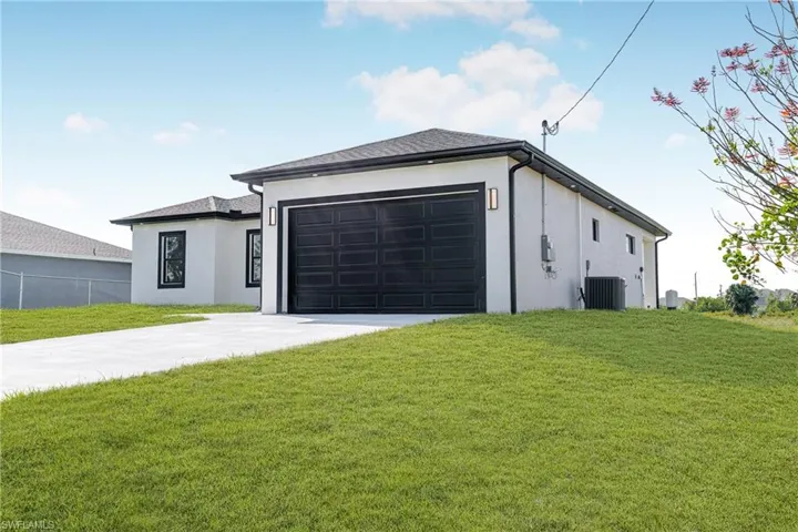 View of front facade featuring concrete driveway, a front lawn, stucco siding, and a garage