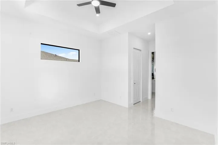 Empty room featuring a raised ceiling, ceiling fan, and recessed lighting