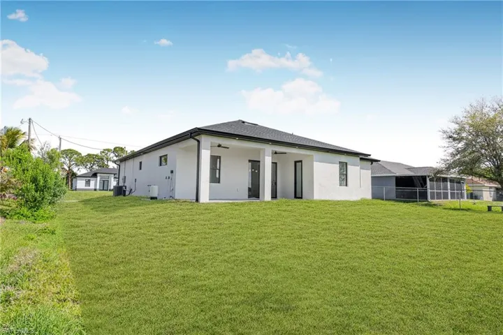 Back of property featuring a lawn, stucco siding, and a patio