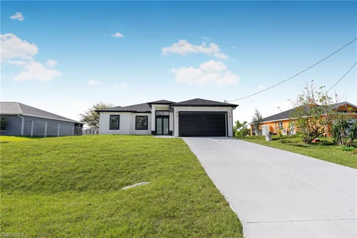 Prairie-style home with concrete driveway, stucco siding, and an attached garage