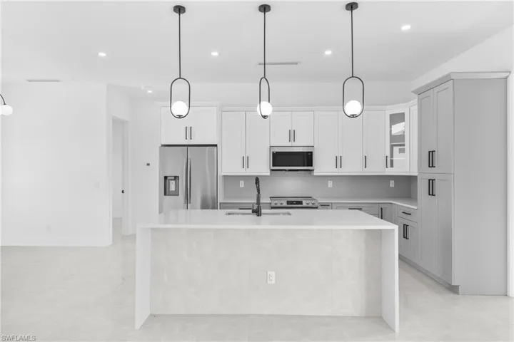 Kitchen featuring tasteful backsplash, pendant lighting, light stone counters, and recessed lighting