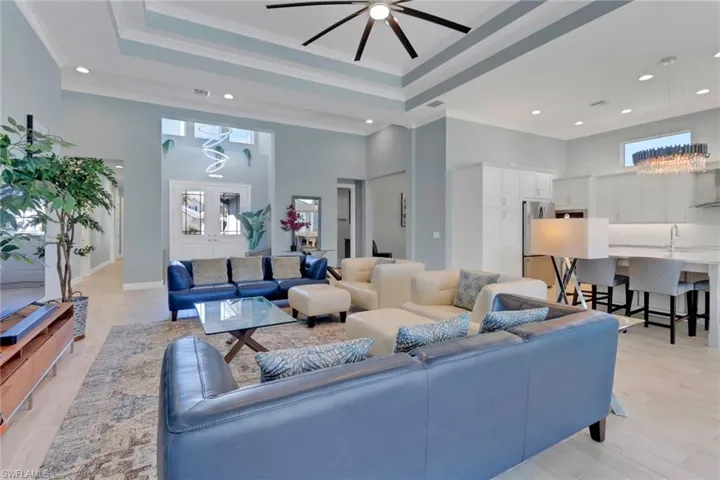 Living room featuring a towering ceiling, crown molding, recessed lighting, ceiling fan, and a chandelier