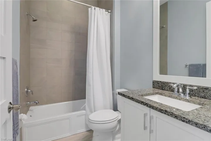 Full bathroom with toilet, shower / bathtub combination with curtain, and vanity