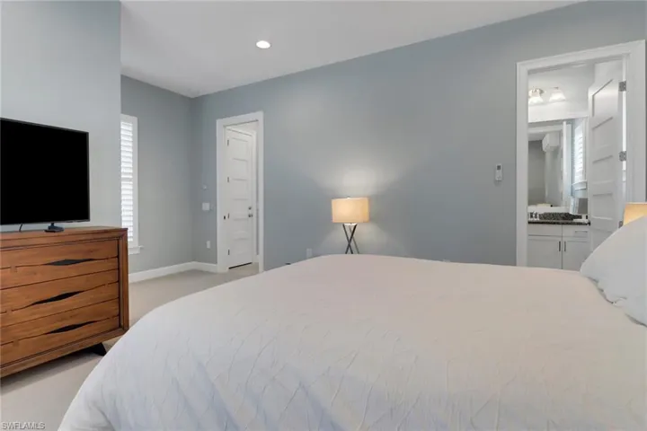 Bedroom featuring baseboards, ensuite bathroom, recessed lighting, and light colored carpet
