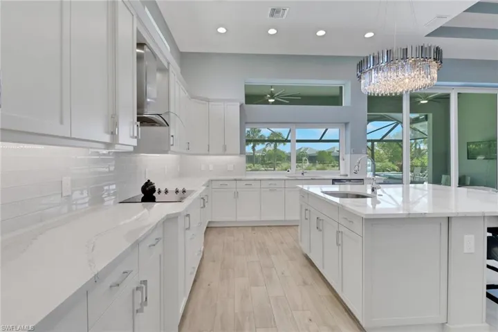 Kitchen with a sink, exhaust hood, ceiling fan, white cabinetry, and decorative backsplash