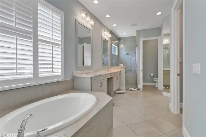Bathroom with a bath, a shower stall, toilet, vanity, and tile patterned floors