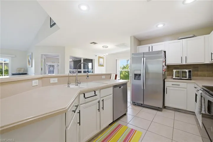 Kitchen with stainless steel appliances, white cabinets, light countertops, tasteful backsplash, and recessed lighting