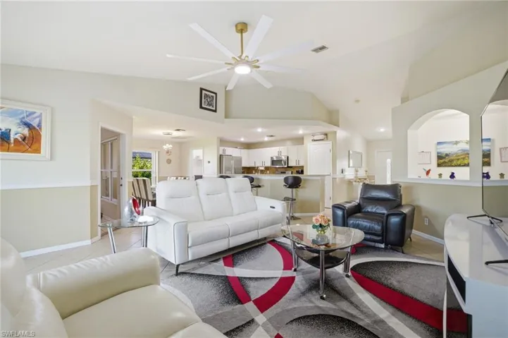Living area with ceiling fan, light tile patterned flooring, and lofted ceiling
