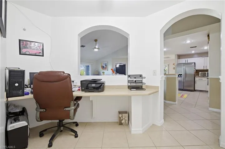 Office area with arched walkways, ceiling fan, light tile patterned flooring, vaulted ceiling, and recessed lighting