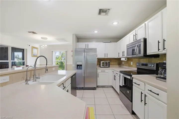 Kitchen with stainless steel appliances, light countertops, white cabinets, light tile patterned flooring, and recessed lighting