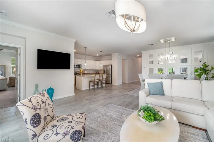 Living area with a chandelier, light wood finished floors, ornamental molding, and recessed lighting